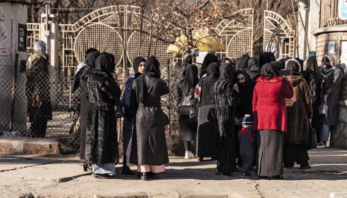A group of Afghan women gather outside a university in the capital a day after they were banned from higher education.— AFP