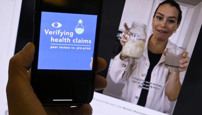 Un'immagine di AFP fact-check su un telefono cellulare accanto a un video TikTok di una finta cura per l'influenza dell'acqua di cipolla.  — AFP