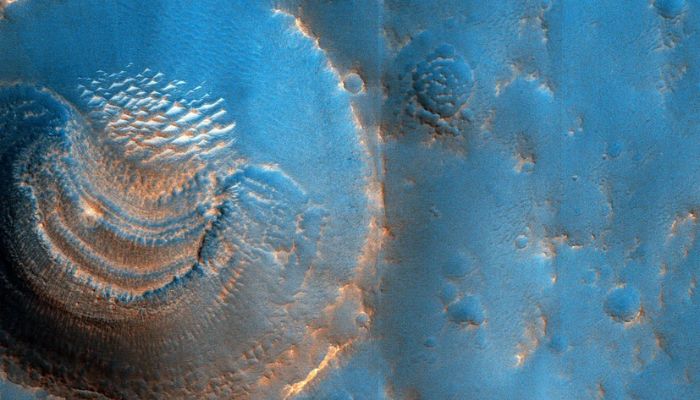 This processed image from the MRO HiRise camera uses distinctive colors to highlight formations and features of a crater with unusual deposits inside it.— NASA, UArizona