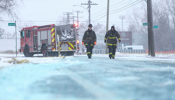 Detroit İtfaiye Departmanına bağlı itfaiyeciler, 23 Aralık 2022'de Amerika Birleşik Devletleri'nin Detroit kentinde çıkan bir depo yangınıyla mücadele ederken yangın hortumlarındaki buzu çıkarmaya çalışıyor.  — AFP