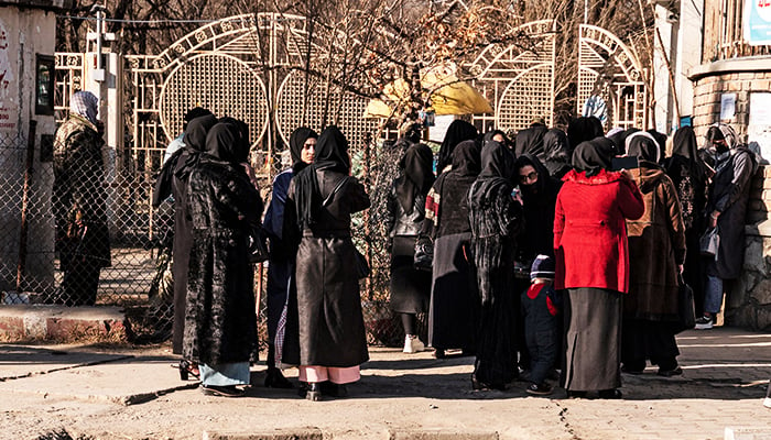 Afghan female university students stop by Taliban security personnel stand next to a university in Kabul on December 21, 2022. — AFP