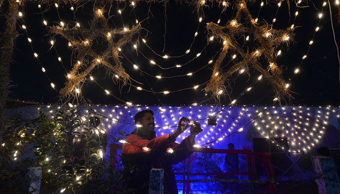 100 çeyrekte Noel kutlamaları öncesinde ışıkları süsleyen bir adam.  - UYGULAMA