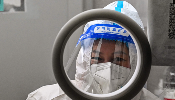 A health worker waits for people to take swab samples to test for the COVID-19 coronavirus in the Jing´an district in Shanghai on December 23, 2022. — AFP