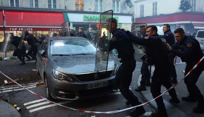 Fransız çevik kuvvet polisi, 23 Aralık 2022'de Paris'te açılan ateş sonucu üç kişinin hayatını kaybetmesinin ardından çıkan çatışmada protestocuları dağıtmak için koştu.— AFP