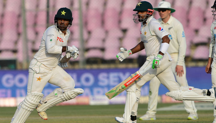 Pakistans Sarfaraz Ahmed (L) and captain Babar Azam run between the wickets during the first day of the first cricket Test match between Pakistan and New Zealand at the National Stadium in Karachi on December 26, 2022. — AFP