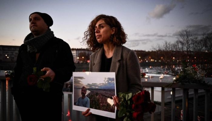 27 Aralık 2022'de Lyon'da İran halkının durumu hakkında farkındalık yaratmak için Rhone Nehri'ne atladıktan sonra kendini öldüren İranlı bir adamın anısına bir kadın elinde fotoğraflı bir portre tutuyor.— AFP