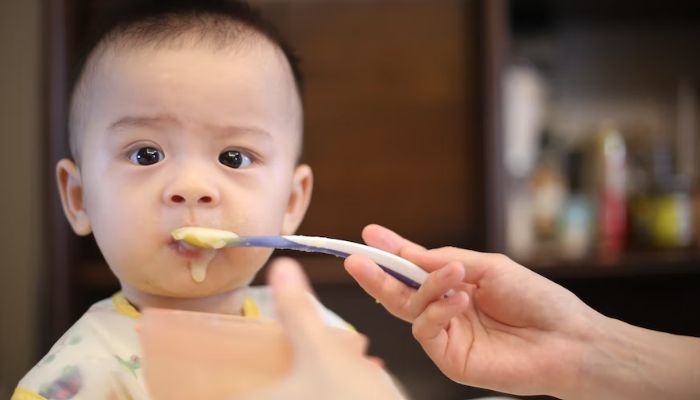A woman feeding a baby with a spoon.— Unsplash