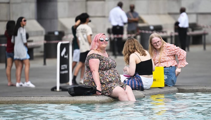 Pedestrians cool off by soaking their feet in the Trafalgar Square fountain in London during a heat wave. — AFP/File