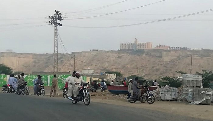İnsanlar, 11 Mayıs 2019'da silahlı kişilerin saldırısına uğrayan Belucistan vilayetindeki bir liman kenti olan Gwadar'daki Pearl Continental Hotel'e yoldan bakıyor. — AFP/ Dosya