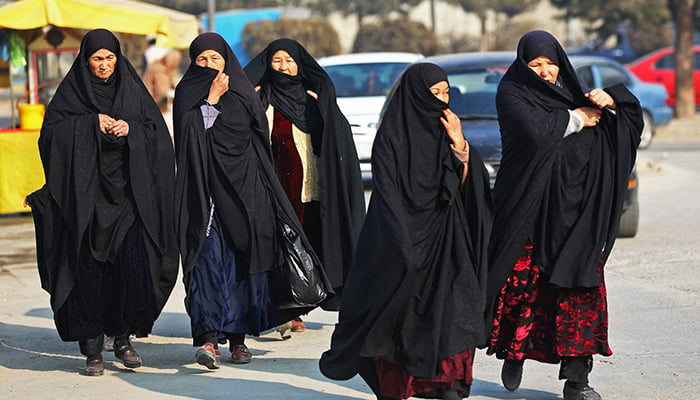 Afghan burqa-clad women walk through a street in Kabul on December 28, 2022. — AFP