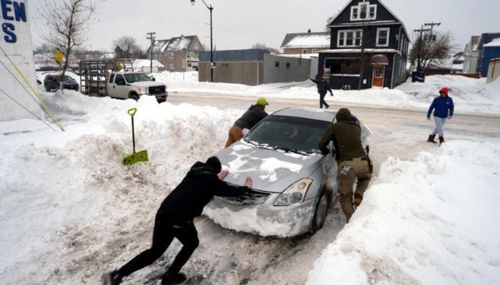 Good Samaritans help to push a car on South Park Avenue in Buffalo, New York.— AFP