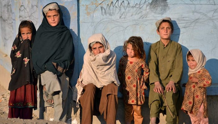 Afgan çocuklar 10 Kasım 2021'de duvara yaslanarak güneşleniyor. — AFP