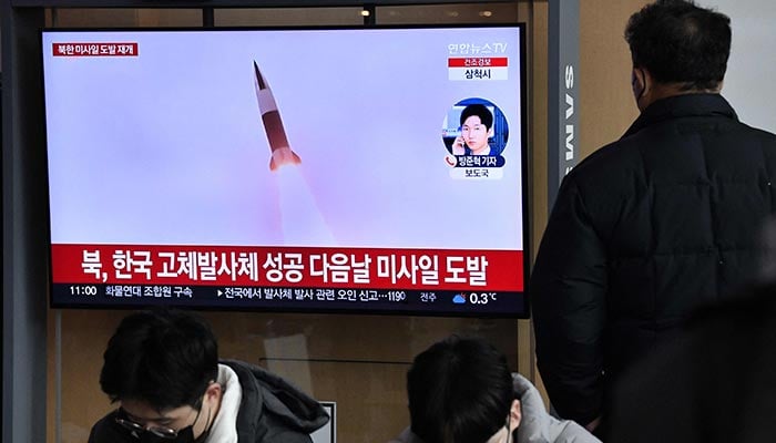 Bir adam, 31 Aralık 2022'de Seul'deki bir tren istasyonunda Kuzey Kore füze testinin dosya görüntülerini içeren bir haber yayınını gösteren bir televizyon ekranını izliyor. — AFP