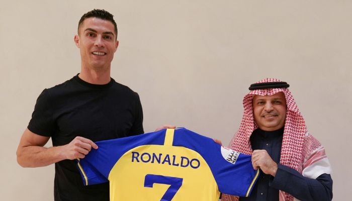 The Portuguese star pictured on the Al Nassr Twitter feed holding a blue and yellow shirt with his favoured number seven printed on the back.— Twitter