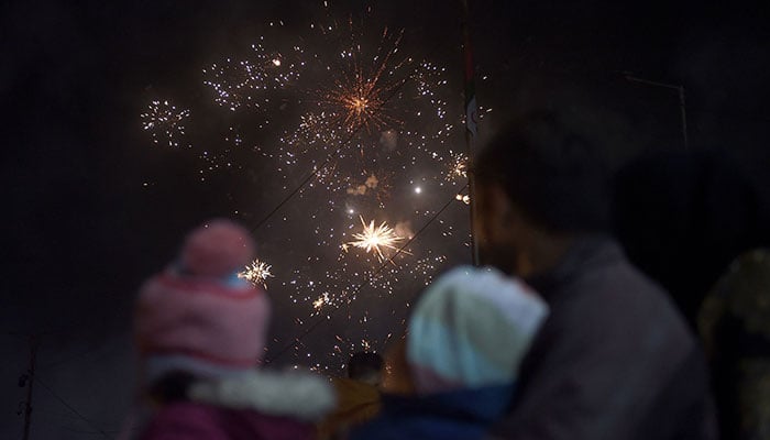 Eğlence tutkunları, 1 Ocak 2023'ün başlarında Karaçi'de Yeni Yıl kutlamaları sırasında bir havai fişek gösterisi izliyor. — AFP