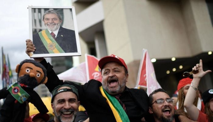 Supporters of President-elect Luiz Inacio Lula da Silva cheer outside the hotel where he is staying on the eve of his inauguration, in Brasilia on December 31, 2022.— AFP