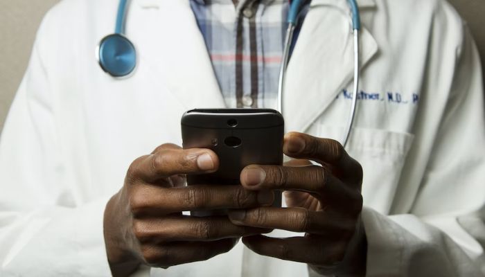The image shows a doctor holding a cell phone.— Unsplash