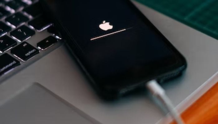 An iPhone being charged on top of a MacBook.— Unsplash