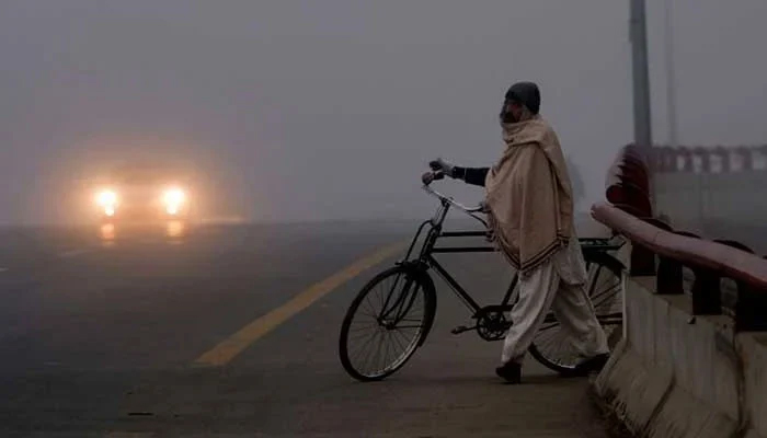 A man standing on a flyover with his bicycle in cold weather — AFP/File