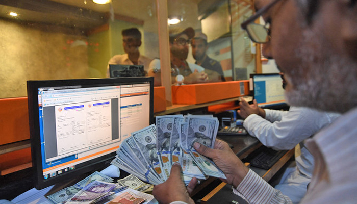 A currency dealer counts dollars at a currency exchange shop in Karachi, on August 1, 2018. — AFP/Files