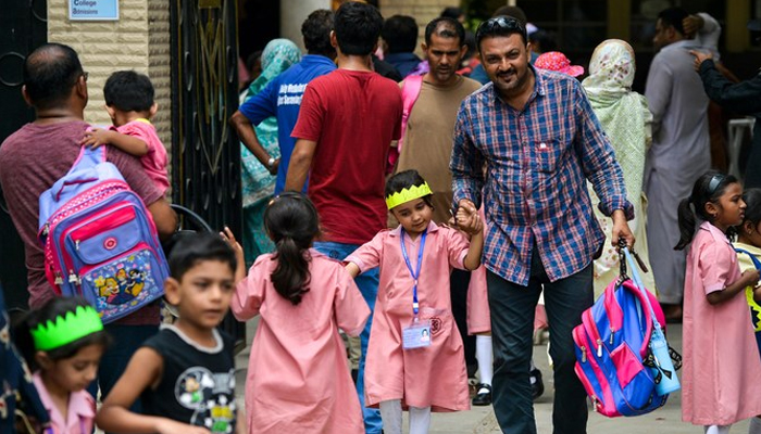 School children leave with their parents at the end of the school day in Karachi on July 1, 2019. — AFP