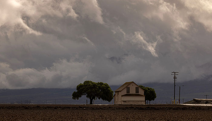 Clouds rise behind a farm near the flooded Salines River during a brief in a storm close to Chualar, California, on August 14, 2023. — AFP