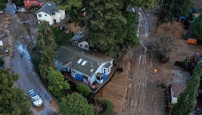 In this aerial picture taken on January 14, 2023, residents clean up their muddy neighborhood in Felton, California. — AFP