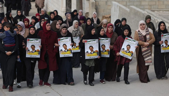 Palestinian women with posters of Ahmad Kahla during his funeral procession in the village of Rammun in the occupied West Bank, on January 15, 2023. — AFP