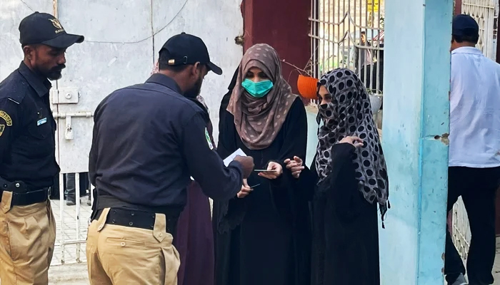 A policeman checks the documents of female votes outside a polling station in Karachi during the local government polls on January 15, 2023. — Geo.tv