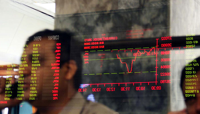 A stockbroker talks on the phone as a trading stream is reflected on a glass screen. — AFP/File  Bloodbath as PSX sheds over 1,400 points amid political uncertainty 1031566 1241014 PSX updates