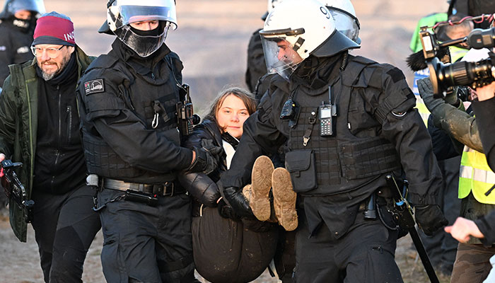 Police officers carry Swedish climate activist Greta Thunberg (C) out of a group of demonstrators and activists in Erkelenz, western Germany, on January 17, 2023. — AFP