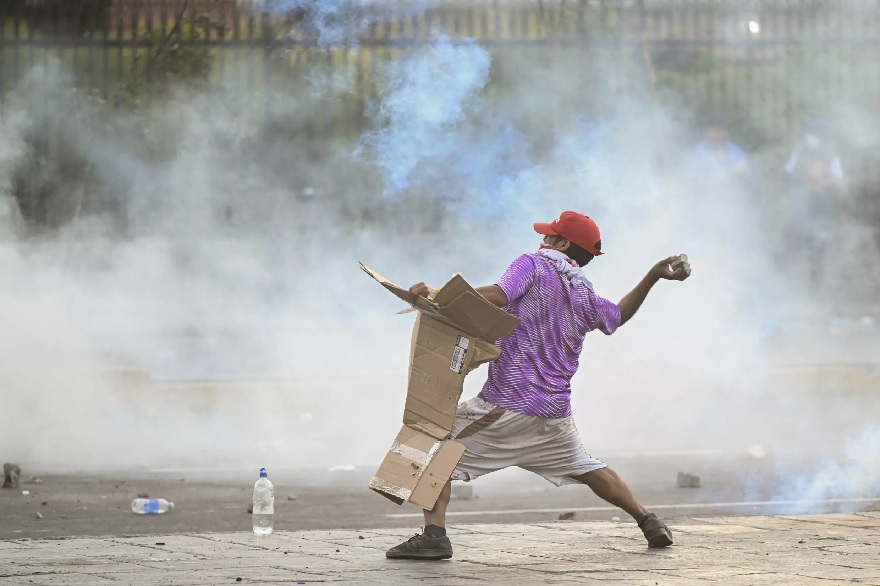 19 Ocak 2023'te Lima'da Başkan Dina Boluarte hükümetine karşı düzenlenen bir protesto sırasında bir gösterici çevik kuvvet polisine taş atıyor.— AFP