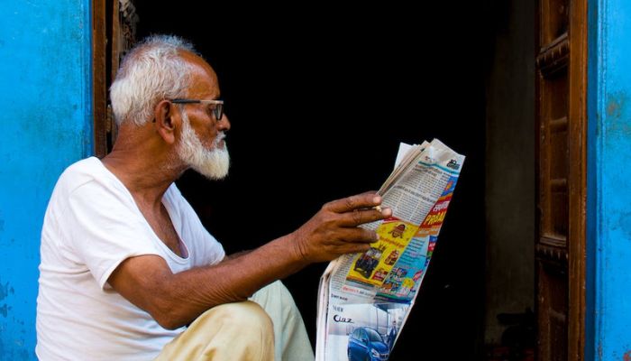 Hindistan, RJ, Bikaner'de bir yerde elinde bir gazete makalesi tutan yaşlı bir adam oturuyor.  - piksel
