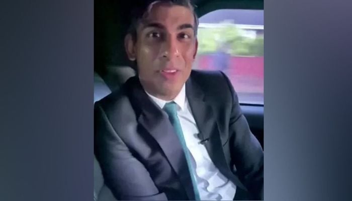 جمعرات کی ویڈیو میں، جو سنک کے سوشل میڈیا چینلز پر تقسیم کے لیے تیار کی گئی ہے، بغیر بیلٹ کے قدامت پسند رہنما چلتی کار کی پچھلی سیٹ سے بول رہے ہیں۔— ٹویٹر اسکرین گریب