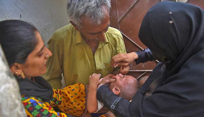 Un operatore sanitario somministra gocce di vaccino antipolio a un bambino durante la campagna di vaccinazione antipolio porta a porta a Karachi il 23 maggio 2022. — AFP