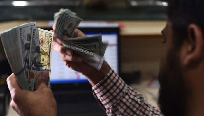 A Pakistani dealer counts US dollars at a currency exchange shop in Karachi on October 9, 2018. — AFP/File