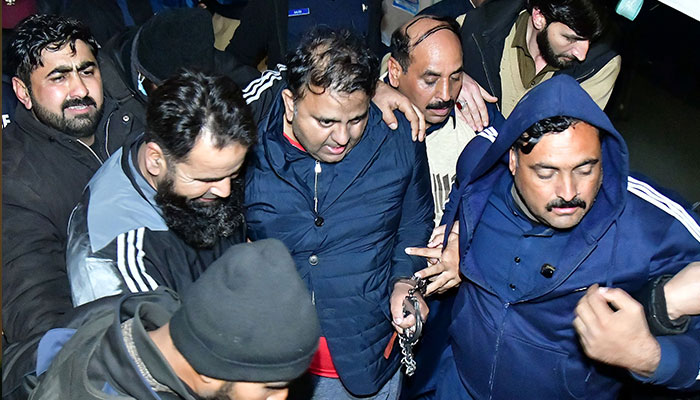 Police officials escort the former information minister Fawad Chaudhry to leaving after hearing in a court, in Federal Capital. — Online/File