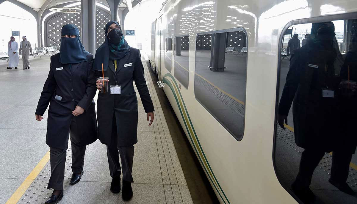 Conductors walk beside a high-speed train ferrying pilgrims to Makkah. — AFP
