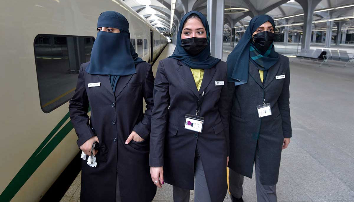 Saudi conductors walk beside the high-speed. — AFP
