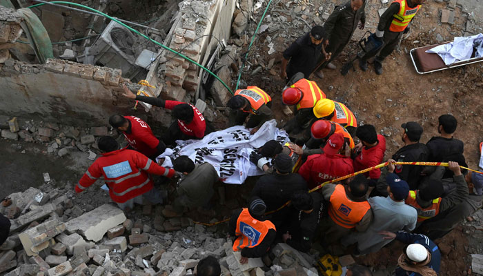 Rescue workers carry the remains of the blast victims from the debris of a damaged mosque after a blast inside the police headquarters in Peshawar on January 30, 2023. — AFP