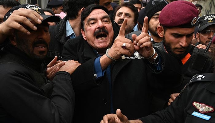 Police officials escort Pakistan´s former interior minister Sheikh Rashid Ahmed (C) to present him before a court in Islamabad on February 2, 2023. — AFP