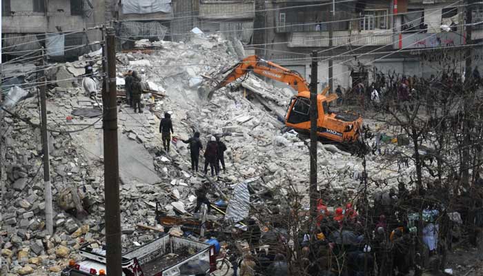 People watch as rescue teams look for survivors under the rubble of a collapsed building after an earthquake in the regime-controlled northern Syrian city of Aleppo on February 6, 2023. — AFP
