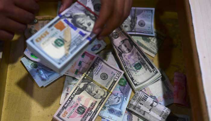A dealer collect US dollars at a money exchange market in Karachi on January 26, 2023. — AFP