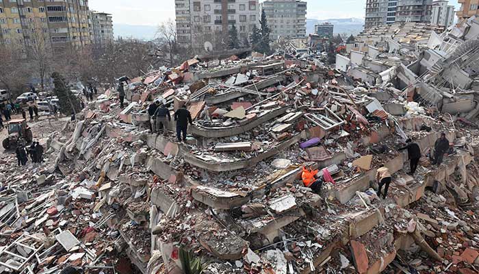 7 فروری 2023 کو ملک کے جنوب مشرق میں آنے والے 7.8 شدت کے زلزلے کے ایک دن بعد، جنوبی ترکی کے کہرامانماراس میں رضاکار تباہ شدہ عمارت کے ملبے پر کھڑے ہیں۔ - اے ایف پی