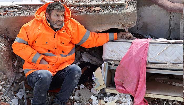 Mesut Hancer holds the hand of his 15-year-old daughter Irmak, who died in the earthquake in Kahramanmaras, close to the quake´s epicentre, the day after a 7.8-magnitude earthquake struck the country´s southeast, on February 7, 2023.. — AFP