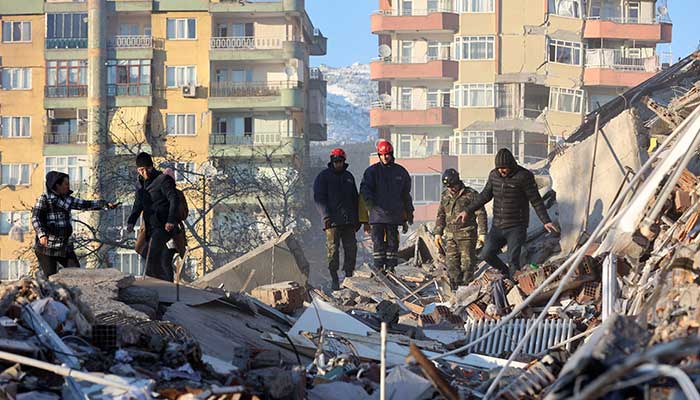 Volunteers stand on rubble of a destroyed building in Kahramanmaras, southern Turkey, a day after a 7.8-magnitude earthquake struck the country´s southeast, on February 7, 2023.. — AFP