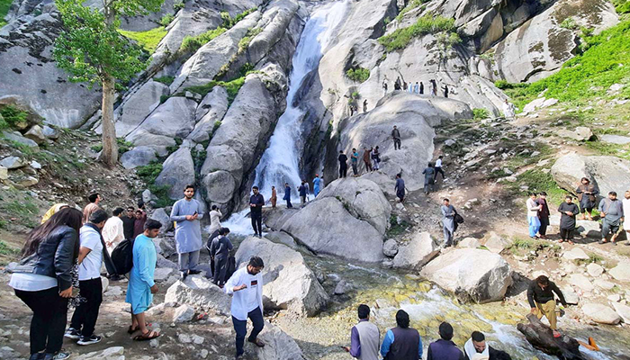A large number of tourists visit a waterfall at Kumrat Valley on May 9, 2023. — APP