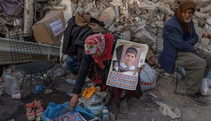 A woman holds photos of her missing grandchildren Hatay, Turkey. — AFP/File