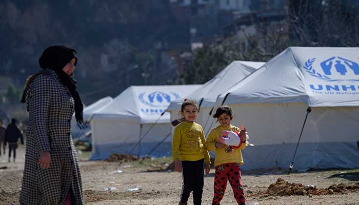 Girls walk by tents in a camp in Antakya, south of Hatay, on February 15, 2023. — AFP