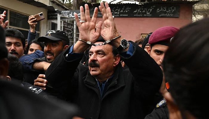 Polis yetkilileri, eski içişleri bakanı Şeyh Raşid Ahmed'e (ortada) 2 Şubat 2023'te İslamabad'daki bir mahkemeye sunulması için eşlik ediyor. — AFP/File